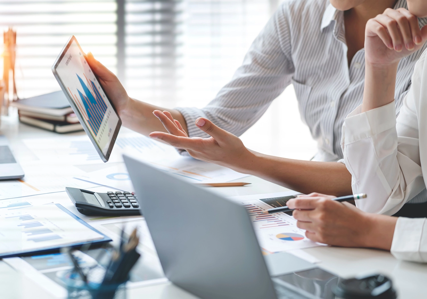 BD Medical Writing & Consulting - Eine Nahaufnahme aus der Vogelperspektive zeigt Kollegen, die auf einem Holzschreibtisch Finanzdokumente mit Diagrammen und Grafiken analysieren.