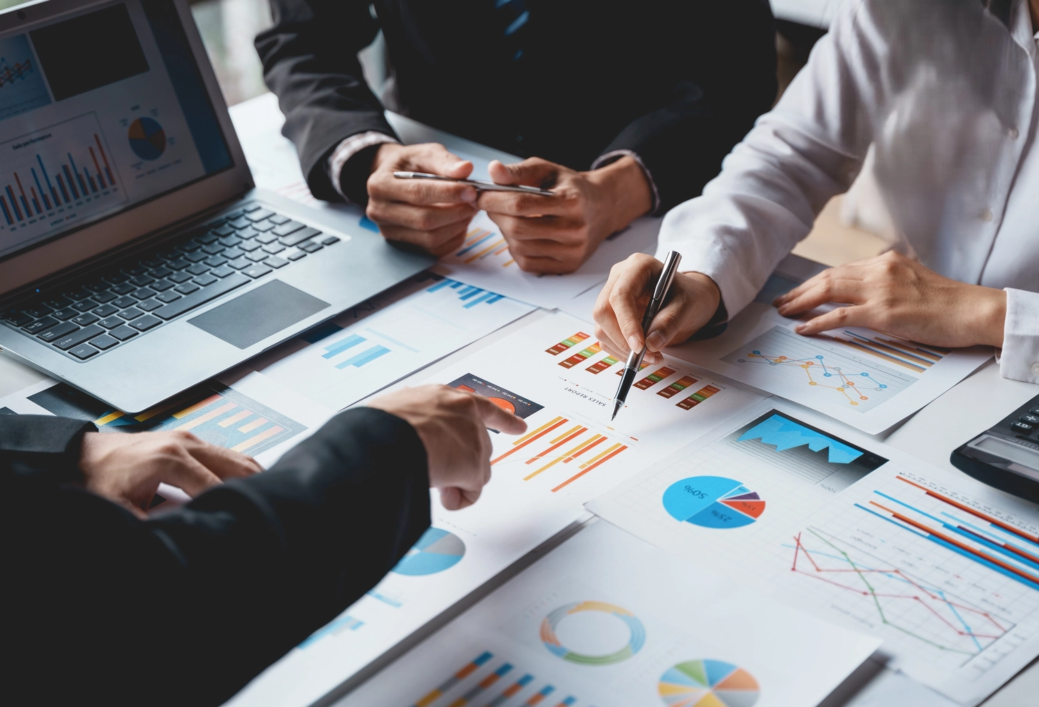 BD Medical Writing & Consulting - Nahaufnahme eines Business-Teams, das Finanzdiagramme und Datenberichte auf einem Tisch auswertet.